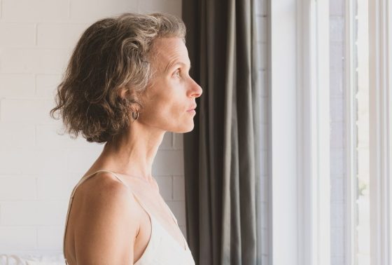 Older woman with short hair looking outside a bright window